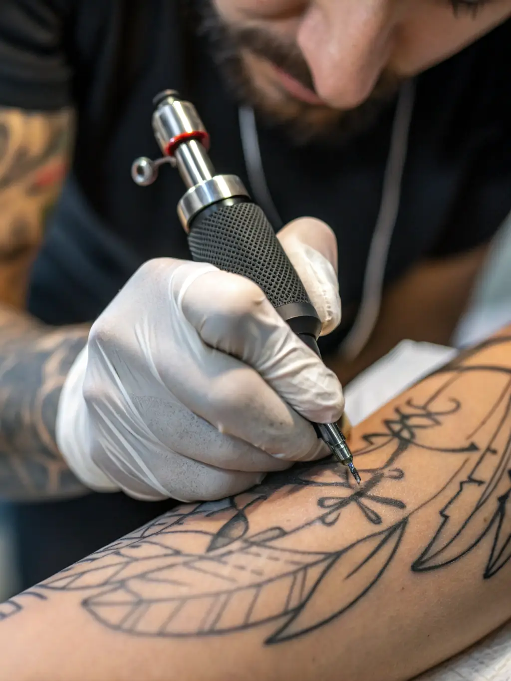 A close-up shot of a tattoo artist's hands meticulously working on a detailed tattoo design.